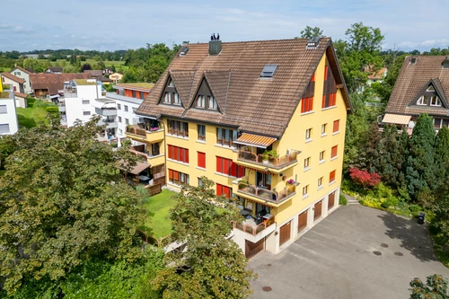 das Mehrfamilienhaus ist umgeben von einer schönen Grünfläche